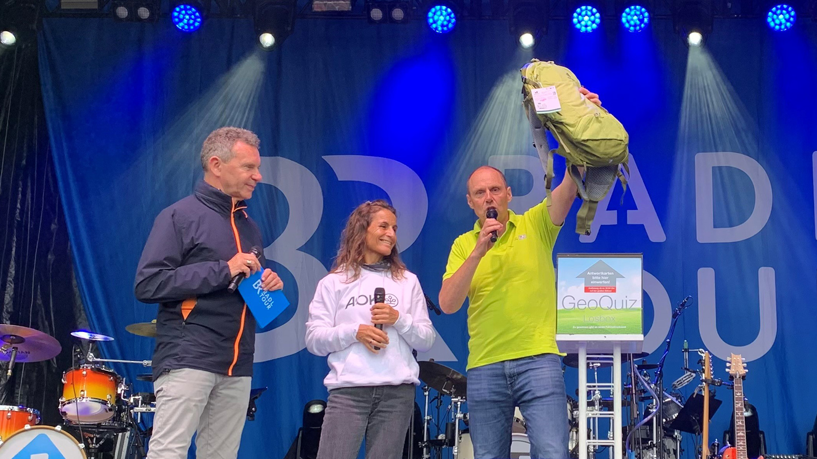 LDBV-Präsident Daniel Kleffel (rechts) auf der BR-Bühne Herr Kleffel hält den Gewinn, einen Grünen Rucksack, in die Luft